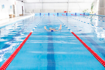 A 70-year-old pensioner is resting, swimming, recovering in the pool with clear and blue water in the hotel.