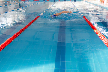 Obraz premium A 70-year-old pensioner is resting, swimming, recovering in the pool with clear and blue water in the hotel.