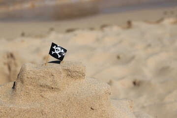 Sand castle at the beach with a pirate flag on a sunny day in vacation time 
