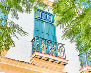 Small balcony with figure iron railings and high door and stained glass window in Old Havana, Cuba.