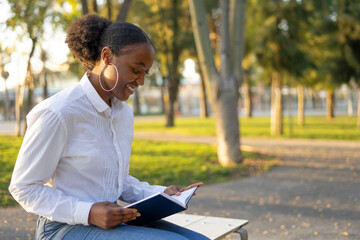 young afro black woman reading a book in the campus of the university