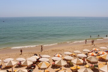 People in vacation at the beach lying under sun umbrellas in the sand and enjoying the view to the ocean 