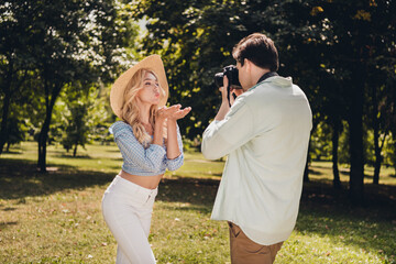 Portrait of two attractive cheerful couple guy taking captures of model posing pastime sending air kiss outdoors