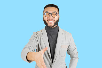 Fototapeta premium handsome asian man with glasses and beard, wearing a businessman's jacket. shaking hands with a confident gesture, blue background