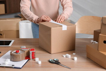 Fototapeta na wymiar Seller taping parcel at workplace, closeup. Online store
