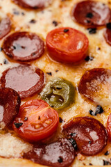 Pizza with smoked sausage, cherry tomatoes, dried chilli, jalapeno peppers and mozzarella. Close up. Copy space