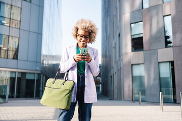 Young african american businesswoman smiling happy using cell phone in the city