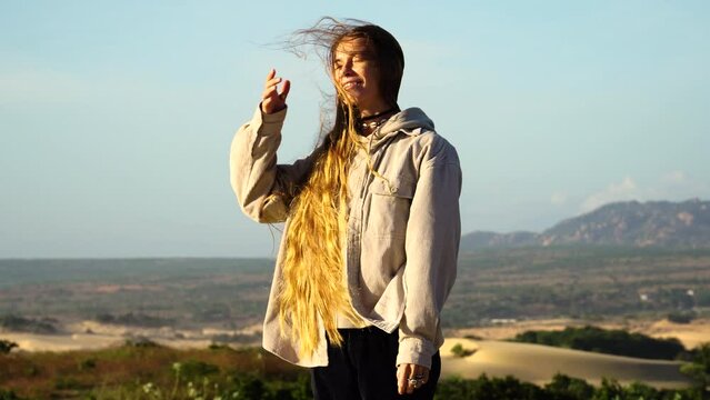 A Woman Sorting Her Long Out in the Wind with Beautiful Background Scenery in Phan Rang, Vietnam on a Summer's Day.