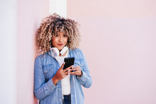 Happy Curvy Hispanic Woman With Afro Hair In City Using Mobile Phone And Headset. Body Positivity