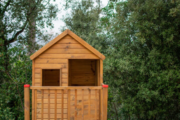 Small wooden house for children in the woods. Playground surrounded by trees. 