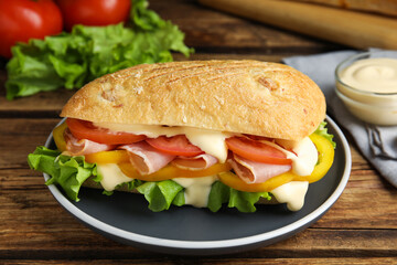 Delicious sandwich with vegetables, ham and mayonnaise served on wooden table, closeup