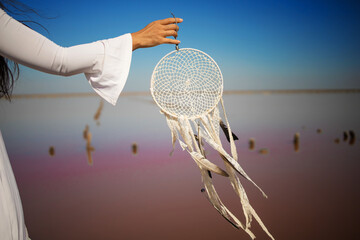 Dreamcatcher at sunset , asian girl boho chic with ethnic amulet at pink sea. symbol peace and harmony.