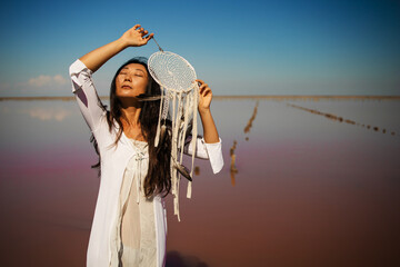 Dreamcatcher at sunset , asian girl boho chic with ethnic amulet at pink sea. symbol peace and...