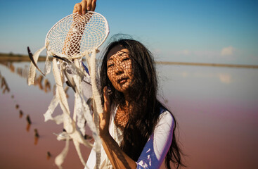 Dreamcatcher at sunset , asian girl boho chic with ethnic amulet at pink sea. symbol peace and...