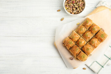 Delicious sweet baklava with pistachios on white wooden table, flat lay. Space for text