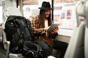 Young man using digital tablet while traveling by a train. Handsome young man traveling by a train.