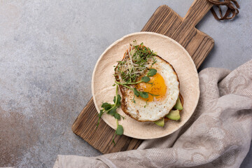 Tasty breakfast of fried egg on toast with avocado and microgreen
