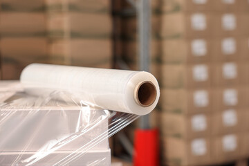 Roll of stretch wrap on box in warehouse, space for text