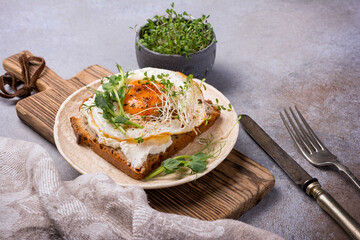 Tasty breakfast of fried egg on toast with microgreen