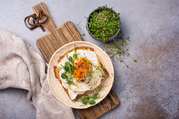 Tasty breakfast of fried egg on toast with microgreen