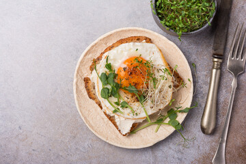 Tasty breakfast of fried egg on toast with microgreen