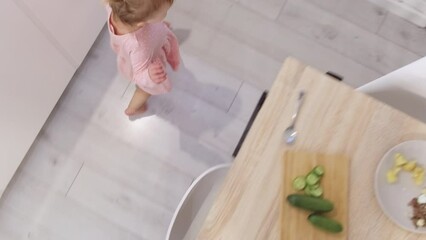 Little cute 2 years old girl having fun running around kitchen table instead of eating, Problems how to feed a child. Top view. 