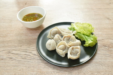 steamed fish dumpling with lettuce on plate dipping spicy and sour sauce