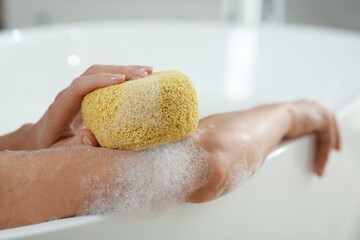 Fototapeta premium Woman with sponge taking bubble bath, closeup