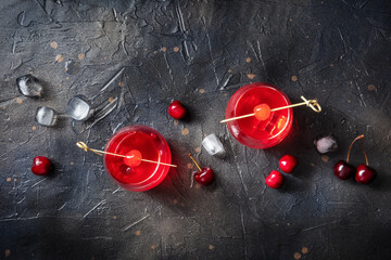 Cocktails with cherries. Alcohol drinks on a black background, with ice. A flat lay with copy space