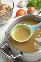 Delicious homemade bone broth and ingredients on white wooden table