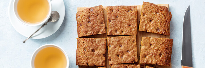Blondie brownie dessert bar with chocolate chips, overhead flat lay panorama with tea