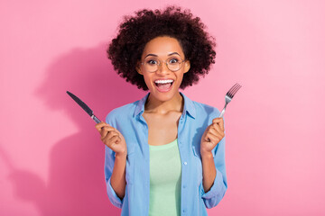Photo of funny hungry lady hold fork knife prepare eat breakfast open mouth wear denim shirt isolated pink color background