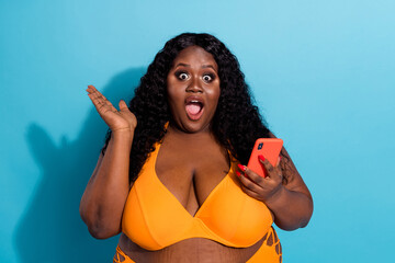 Portrait of pretty amazed cheerful fat woman using device browsing media smm post isolated over...