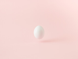 Fototapeta na wymiar White egg floating over pink background. Minimal concept.
