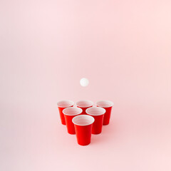 Six red plastic beer pong cups with white ball hovering above.
