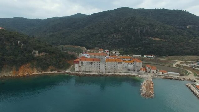 The Esfigmen monastery of Athos against the background of the clear blue waters of the Aegean Sea and mountains covered with forests.