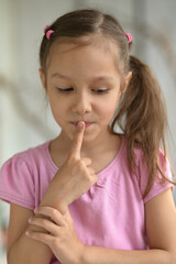 Naklejka premium cute little girl with silence gesture at home