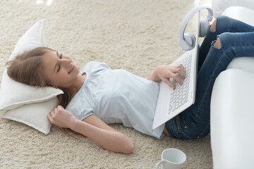 Cute girl using laptop while lying at home