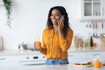 Happy black woman having breakfast and talking on phone