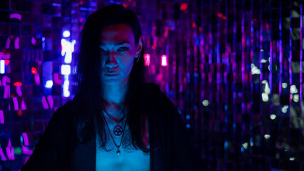 Portrait of a transgender model with a naked torso in a studio with neon lighting.