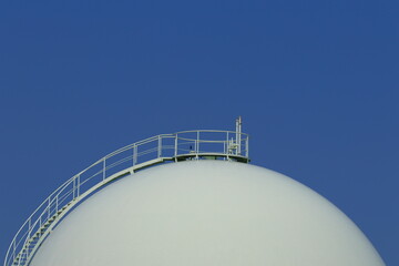 青空とガスタンクを望遠で写す。ガスタンクの球体と階段は、まるでコンビナートの様です。Take a telephoto shot of the blue sky and the gas tank. The sphere and stairs of the gas tank are like a complex.