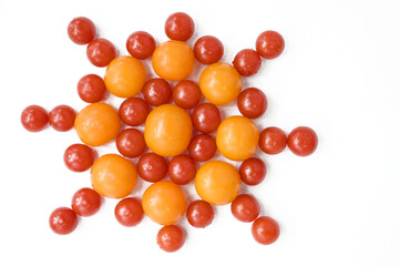 Red and yellow tomatoes stacked on a white table in the form of a flower. Flat lay, top view, close up, macro