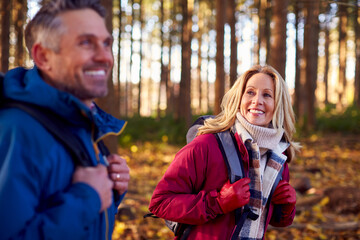 Side View Of Mature Retired Couple With Backpacks Walking Through Fall Or Winter Countryside