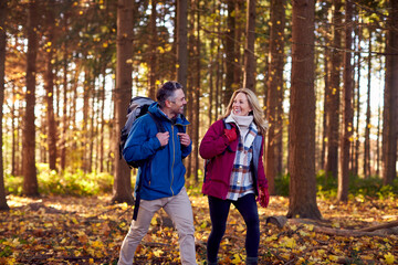 Mature Retired Couple With Backpacks Walking Through Fall Or Winter Countryside