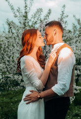 Young beautiful wedding couple walking in the night alley of flowering trees.