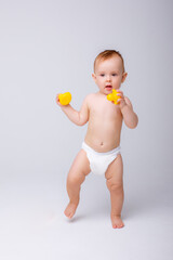 cute baby girl in a diaper playing with a rubber toy duck isolated on a white background