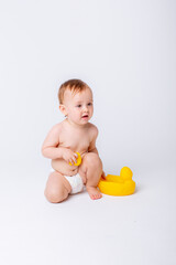 cute baby girl in a diaper playing with a rubber toy duck isolated on a white background