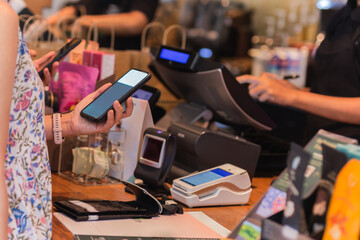 Woman paying bill through smartphone using NFC technology in a restaurant.