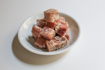 Uncooked diced beef, on a white small plate, isolated on white background
