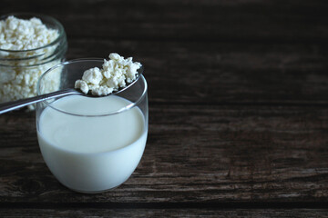homemade cottage cheese with kefir in a glass glass with a spoon on a wooden background